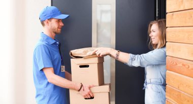 Mavi üniformalı gülümseyen kurye servis konseptine paket kutusu teslim eden teslimatçı. Mavi üniformalı gülümseyen teslimatçı.