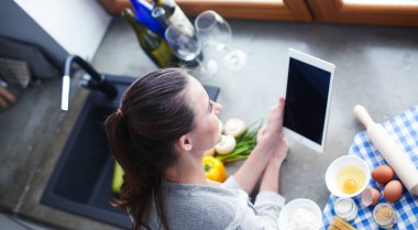 Güzel bir kadın mutfakta pasta pişiriyor. Masanın yanında duruyor..