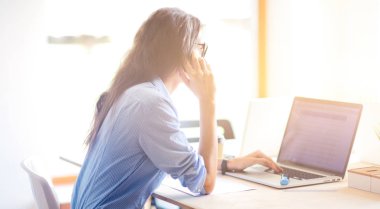 Ofis masasında oturan ve cep telefonuyla konuşan genç ve güzel bir iş kadını. İş kadını