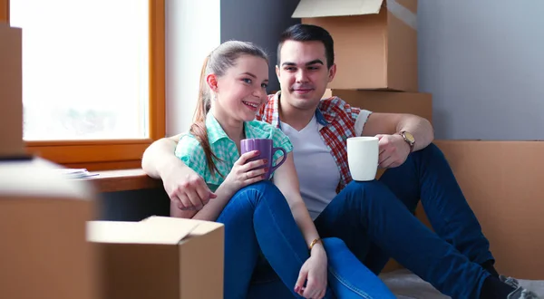 Couple moving in house sitting on the floor. Couple