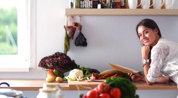 Mujer joven leyendo libro de cocina en la cocina, en busca de receta. Mujer joven —  Fotos de Stock