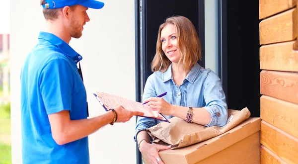 Mavi üniformalı gülümseyen kurye servis konseptine paket kutusu teslim eden teslimatçı. Mavi üniformalı gülümseyen teslimatçı.
