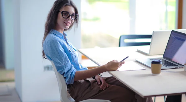 美しい若いビジネスマンの女性がオフィスの机に座って携帯電話で話しています。実業家 — ストック写真