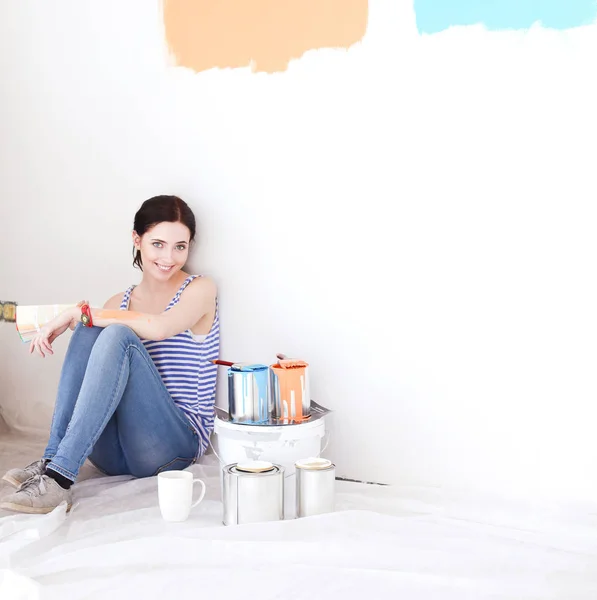 Mujer eligiendo el color de la pintura de la muestra para el nuevo hogar sentado en el suelo de madera. Mujer en la casa — Foto de Stock