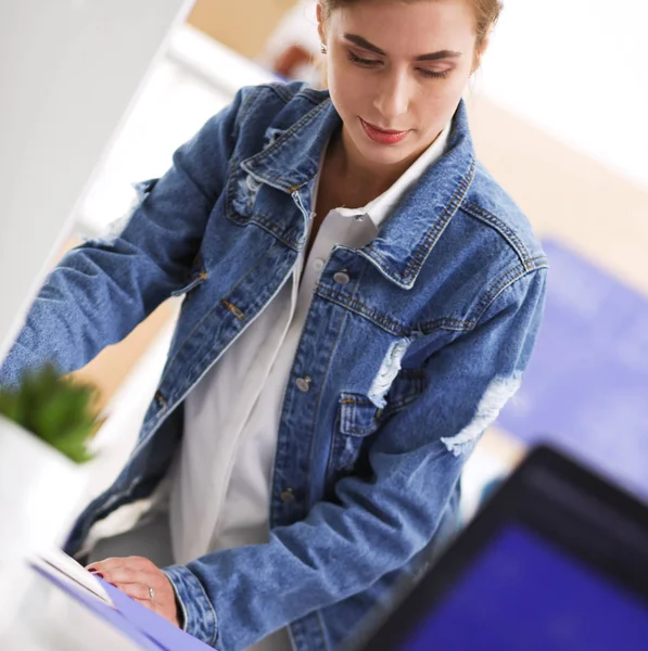 Masanın yanında duran iki genç kadın enstrüman, plan ve dizüstü bilgisayarla.