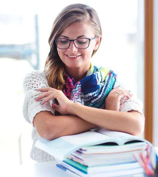 Jonge vrouw zit achter een bureau tussen de boeken. Studenten — Stockfoto