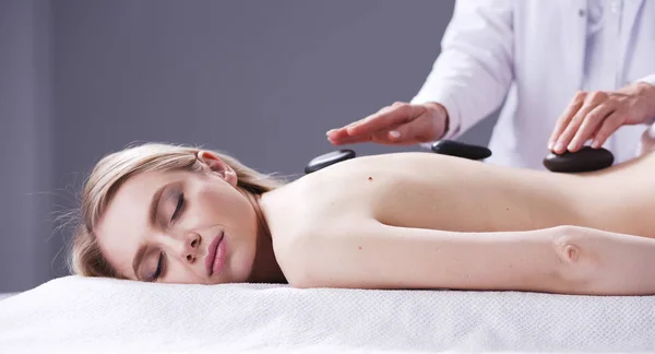 Jovem deitada em uma mesa de massagem, relaxando com os olhos fechados. Mulher. Salão de Spa — Fotografia de Stock