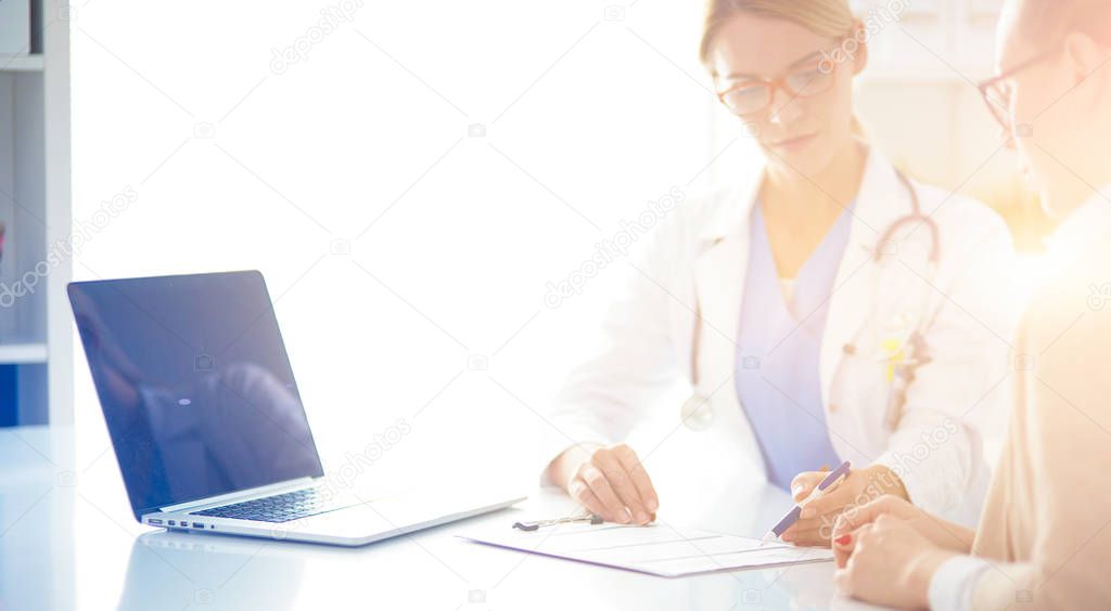 Doctor and patient couple are discussing something,sitting on the desk.