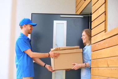 Mavi üniformalı gülümseyen kurye servis konseptine paket kutusu teslim eden teslimatçı. Mavi üniformalı gülümseyen teslimatçı..