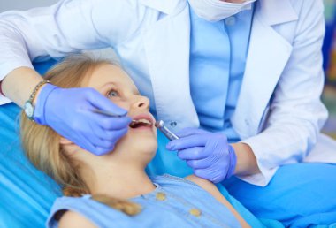 Küçük kız dişçi ofisinde oturuyor..