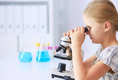 kız öğrenci fen bilgisi dersinde mikroskop aramak.