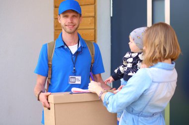 Mavi üniformalı gülümseyen kurye servis konseptine paket kutusu teslim eden teslimatçı. Mavi üniformalı gülümseyen teslimatçı.