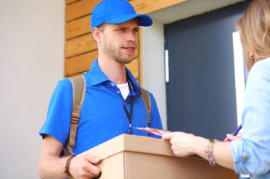 Mavi üniformalı gülümseyen kurye servis konseptine paket kutusu teslim eden teslimatçı. Mavi üniformalı gülümseyen teslimatçı.