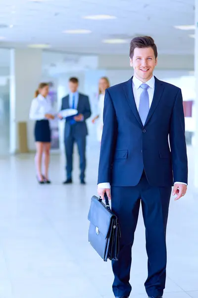 Porträt eines jungen Geschäftsmannes im Amt mit Kollegen im Hintergrund. Porträt eines jungen Geschäftsmannes. — Stockfoto