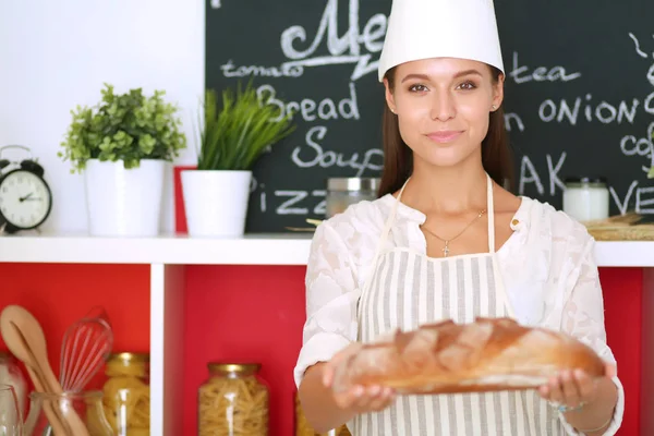 Eine junge Frau steht in ihrer Küche und hält Brot. eine junge Frau — Stockfoto