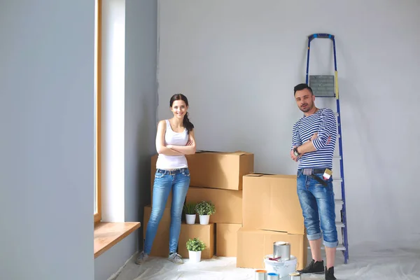 Портрет щаслива усміхнена молода пара малює внутрішню стіну нового будинку. Молода пара — стокове фото