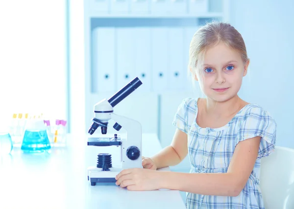 Écolière regardant à travers le microscope en classe de sciences . — Photo