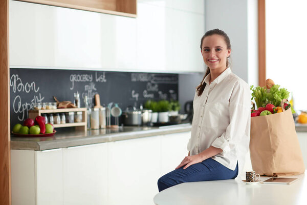 Young woman planning expenses and paying bills on her kitchen.