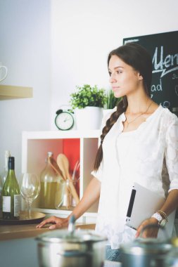 Mutfağında yemek için bir tablet bilgisayar kullanan genç kadın. Genç kadın .