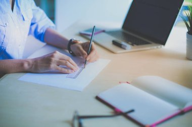 Ofis masasında dizüstü bilgisayarla oturan genç bir kadın. Genç bir kadın. Dizüstü bilgisayar