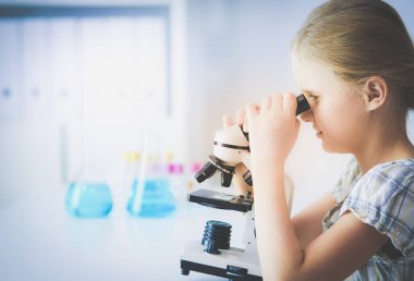 kız öğrenci fen bilgisi dersinde mikroskop aramak.