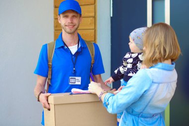 Mavi üniformalı gülümseyen kurye servis konseptine paket kutusu teslim eden teslimatçı. Mavi üniformalı gülümseyen teslimatçı.