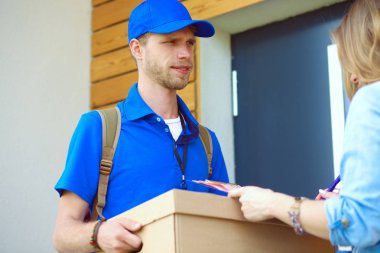 Mavi üniformalı gülümseyen kurye servis konseptine paket kutusu teslim eden teslimatçı. Mavi üniformalı gülümseyen teslimatçı.