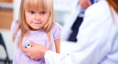 Kadın doktor ameliyatta steteskopla çocuğu muayene ediyor.