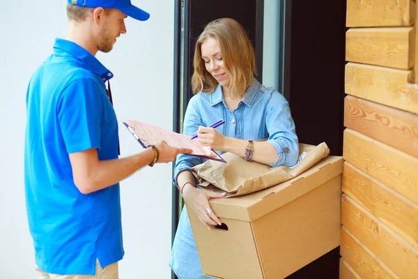 Mavi üniformalı gülümseyen kurye servis konseptine paket kutusu teslim eden teslimatçı. Mavi üniformalı gülümseyen teslimatçı.
