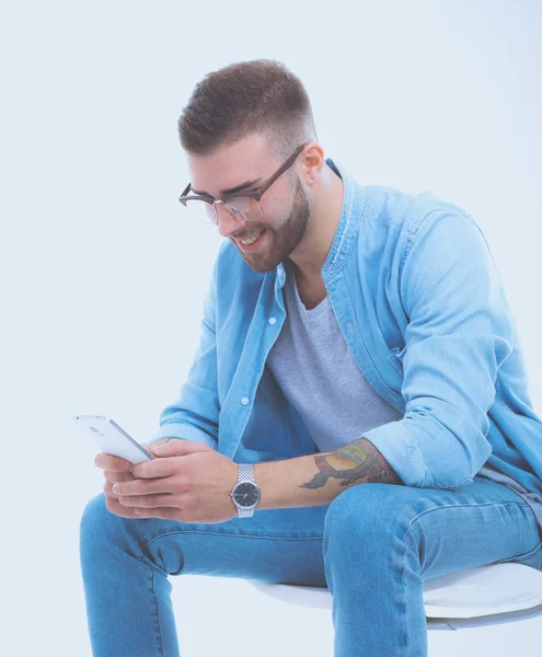 Ung man sitter på stol och med hjälp av mobiltelefon. Startupper. Ung entreprenör. — Stockfoto