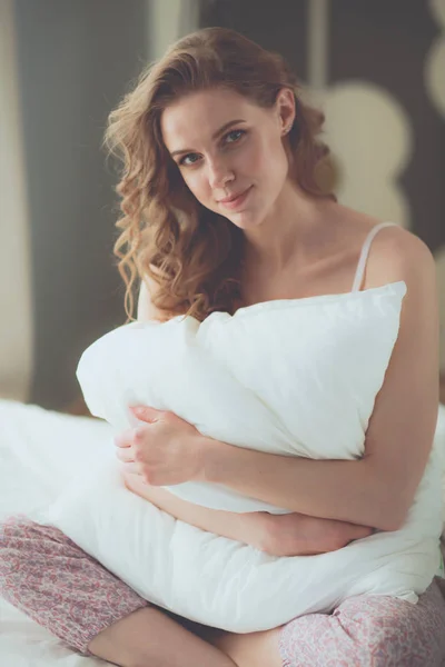 젊은 여자는 동안 그녀의 침대에 앉아 베개를 들고. — 스톡 사진