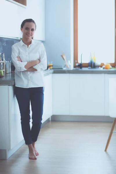 Porträtt av ung kvinna som står med armarna korsade mot kök bakgrund. Kvinna i köket. — Stockfoto