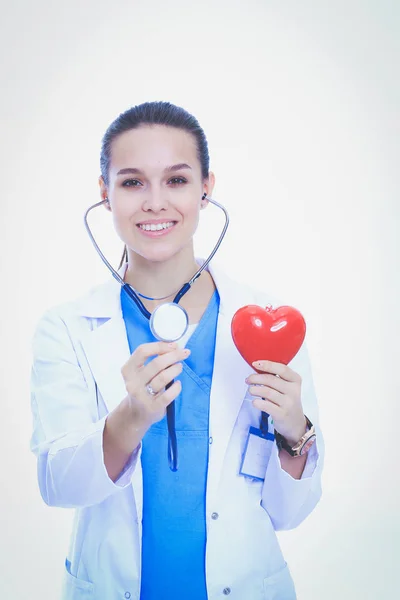 Positieve vrouwelijke arts met de stethoscoop en rood hartsymbool staan geïsoleerd. Vrouw arts — Stockfoto