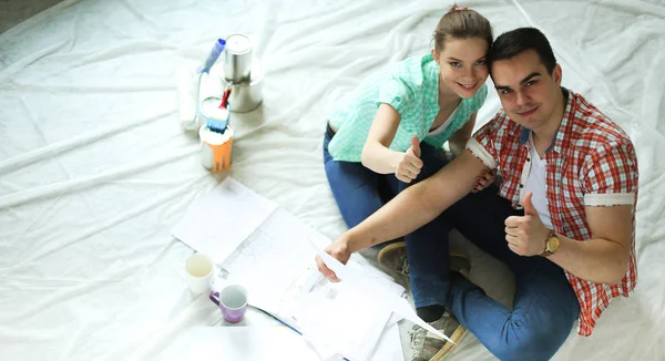 Junges Paar sitzt auf dem Boden und rechnet über seine Ersparnisse — Stockfoto
