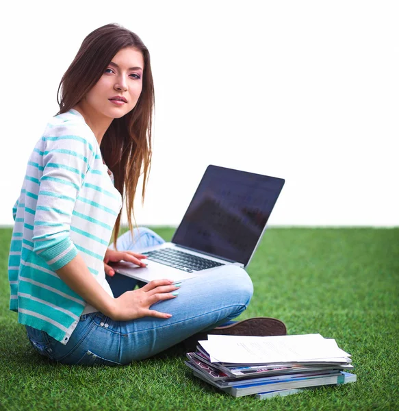 Laptoplu genç bir kadın yeşil çimlerde oturuyor. — Stok fotoğraf