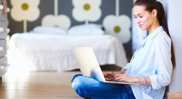 Jonge vrouw zittend op de vloer in de buurt van childrens kinderbed met laptop. Jonge moeder — Stockfoto