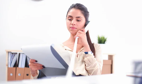 Jovem empresária sentada na mesa e conversando ao telefone — Fotografia de Stock