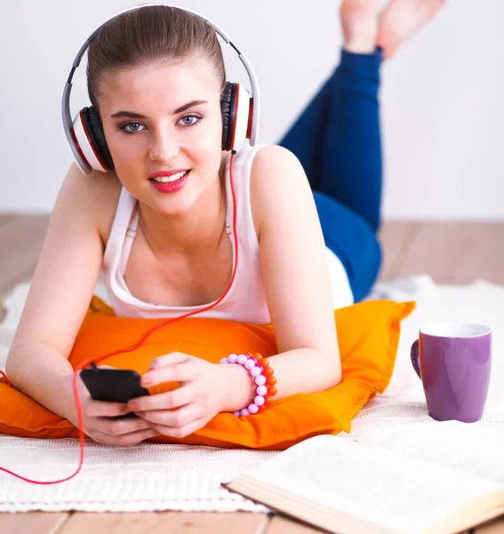 Mujer joven tumbada en el suelo y escuchando música — Foto de Stock