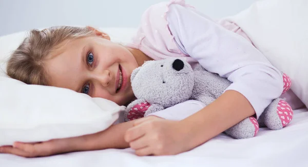 Kleines Mädchen schläft im Bett mit einem Spielzeug-Teddybär. — Stockfoto