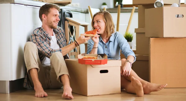 Young couple have a pizza lunch break on the floor after moving into a new home with boxes around them. Young couple — Stock Image Young couple have a pizza lunch break on the floor after moving into a new home with boxes around them. Young couple Royalty Free Stock Images