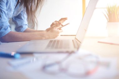 Ofis masasında oturan ve cep telefonuyla konuşan genç ve güzel bir iş kadını. İş kadını