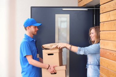 Mavi üniformalı gülümseyen kurye servis konseptine paket kutusu teslim eden teslimatçı. Mavi üniformalı gülümseyen teslimatçı.