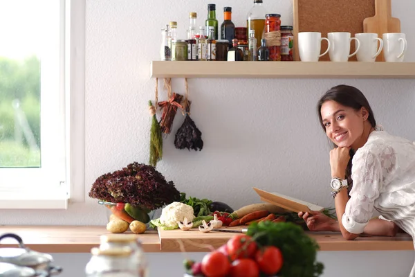 Mujer joven leyendo libro de cocina en la cocina, en busca de receta. Mujer joven —  Fotos de Stock