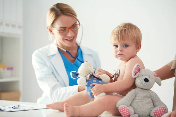 Женщина-врач слушает ребенка со стетоскопом в клинике — стоковое фото