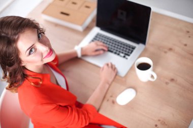 Ofiste oturan çekici bir kadın, dizüstü bilgisayarla çalışıyor.