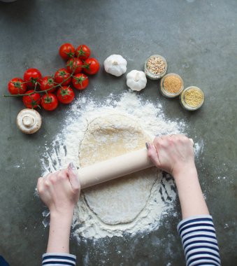 Güzel bir kadın mutfakta pasta pişiriyor. Masanın yanında duruyor..