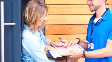 Mavi üniformalı gülümseyen kurye servis konseptine paket kutusu teslim eden teslimatçı. Mavi üniformalı gülümseyen teslimatçı.