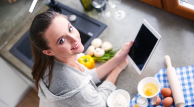 Güzel bir kadın mutfakta pasta pişiriyor. Masanın yanında duruyor..