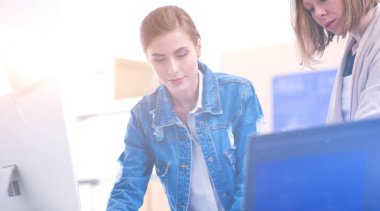 Masanın yanında duran iki genç kadın enstrüman, plan ve dizüstü bilgisayarla.