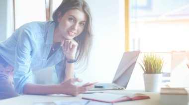 Ofis masasında oturan ve cep telefonuyla konuşan genç ve güzel bir iş kadını. İş kadını